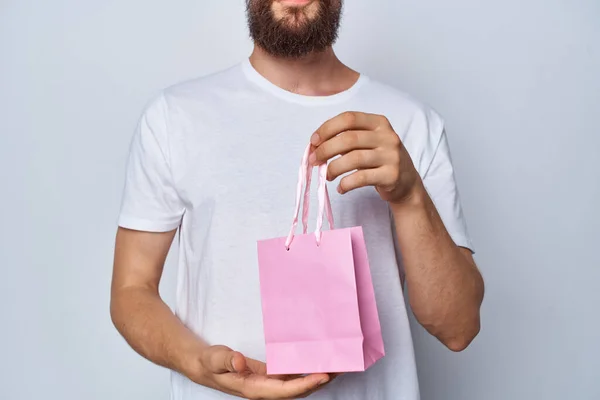 Homem de t-shirt branca presente pacote rosa mostra outro — Fotografia de Stock