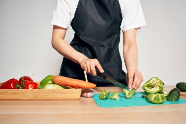 Mutfaktaki ev hanımı salata için sebze doğruyor.