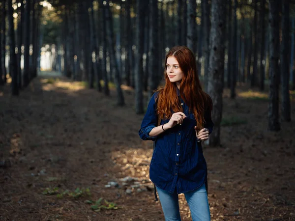 Fröhliche rothaarige Frau mit Rucksack im Wald unterwegs — Stockfoto