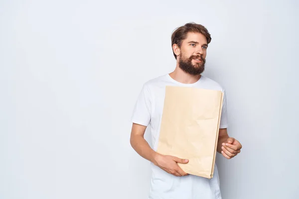 man with paper bag in hand on  light background. High quality photo