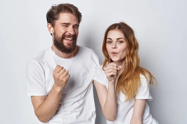 Woman and man in white t-shirts are standing next to fun family studio — Stock Photo, Image