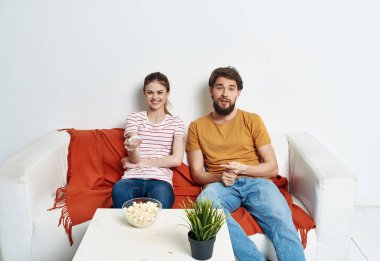 Genç bir çift kanepede oturup mısır patlatıyor ve bir film seyrediyor.