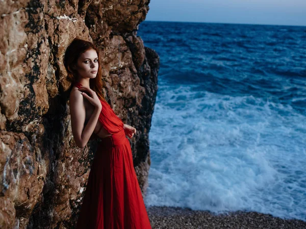 Hübsche Frau in rotem Kleid posiert in der Nähe von Klippen Strand Urlaub Romantik — Stockfoto
