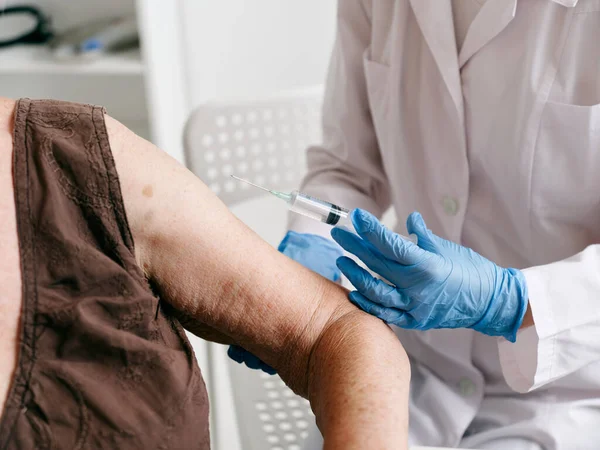 Sjuksköterska som ger en injektion i handen på en äldre kvinna närbild vaccin pass — Stockfoto