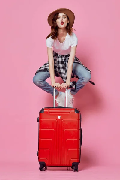 Vrolijke vrouw toerist zit op een rode koffer vlucht luchthaven — Stockfoto
