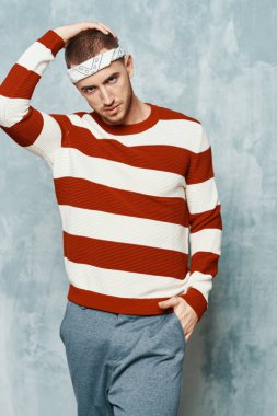 Çizgili süveter giyen yakışıklı bir adam moda özgüveni gösteriyor.