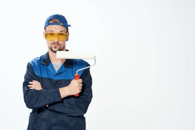 Çalışan üniformalı bir adam duvarları boyuyor, evi onarıyor.
