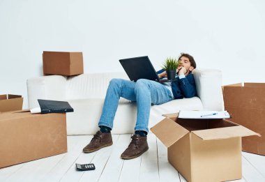 Yönetici elinde dizüstü bilgisayarla koltukta oturuyor. Eşyaları yerleştiriyor.