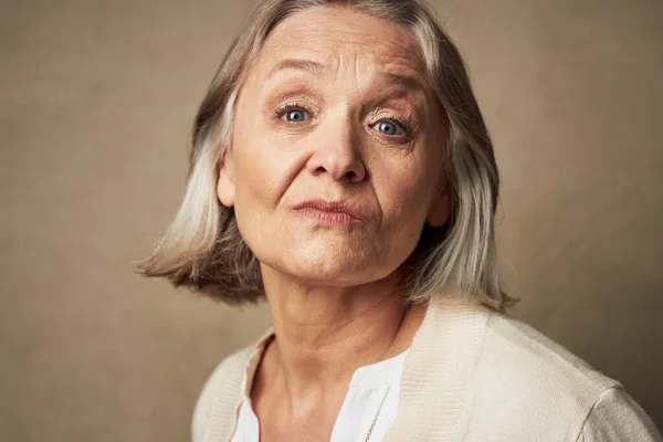 Starsza kobieta w szlafroku twarz zbliżenie stwarzające odosobnione tło — Zdjęcie stockowe