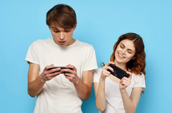 Mann und Frau stehen neben dem Telefon in den Händen Kommunikationstechnologie blauer Hintergrund — Stockfoto