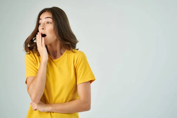 Брюнетка с открытым ртом в желтой футболке обрезанный вид светлый фон — стоковое фото
