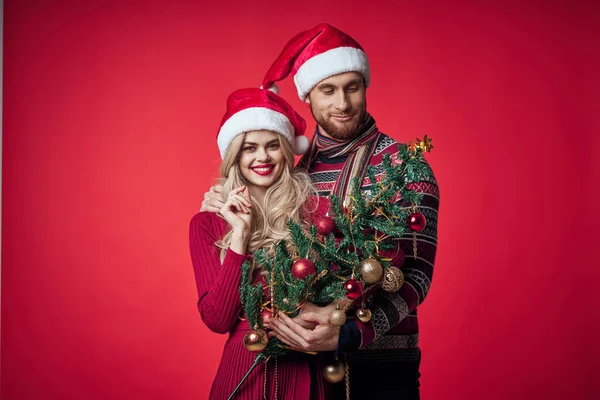 Retrato de um jovem casal em um feriado abraço natal fundo vermelho — Fotografia de Stock