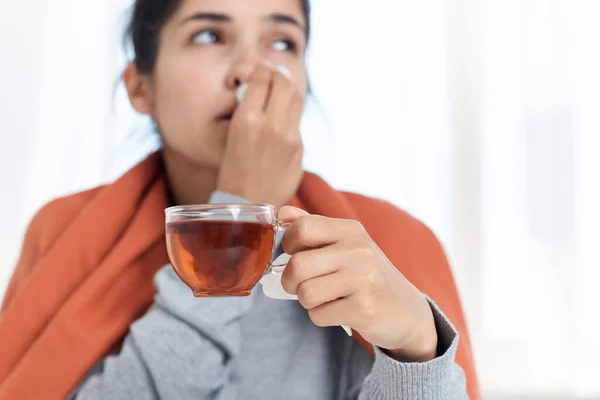Kvinna täckt med en filt kall piller behandling kopp te i händerna — Stockfoto