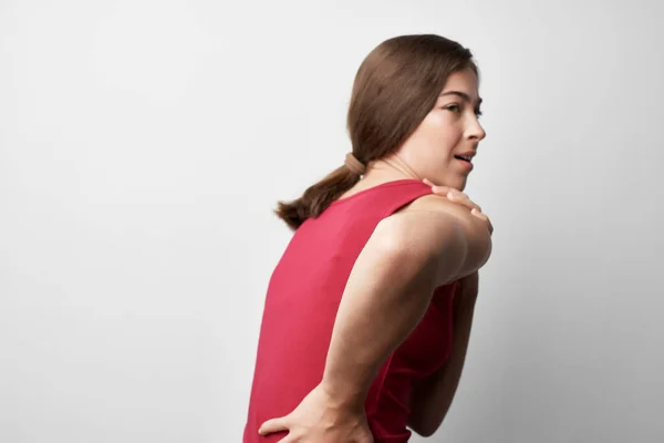 Kırmızı tişörtlü kadın sırt ağrısı çekiyor. Sağlık sorunları, romatizma tıp yaşam tarzı. — Stok fotoğraf
