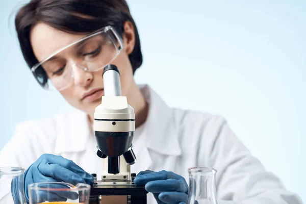 Assistente de laboratório feminino em um casaco branco com um microscópio nas mãos de uma tecnologia de medicina profissional — Fotografia de Stock