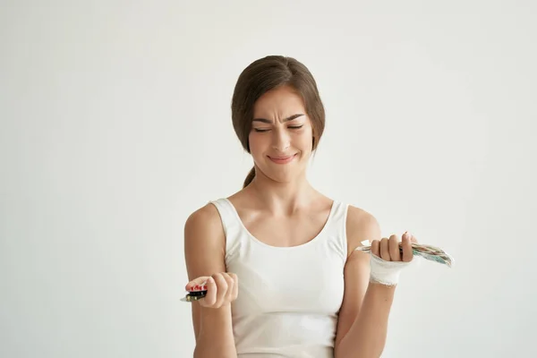 Kvinna med piller i händerna i vit t-shirt skadad hand hälsa medicin — Stockfoto