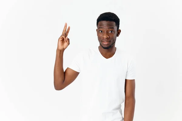 Afrika görünümlü bir adam el hareketleriyle beyaz tişört stüdyosunun izole edilmiş arka planına işaret ediyor. — Stok fotoğraf