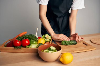 Mutfaktaki ev hanımı salata için sebze doğruyor.