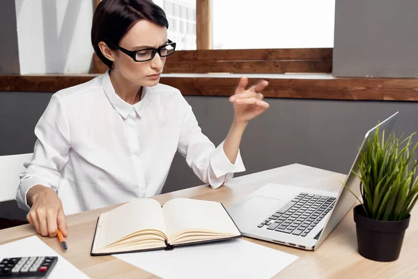 Secretário de mulher de negócios na camisa branca senta-se em uma mesa na frente de um laptop — Fotografia de Stock