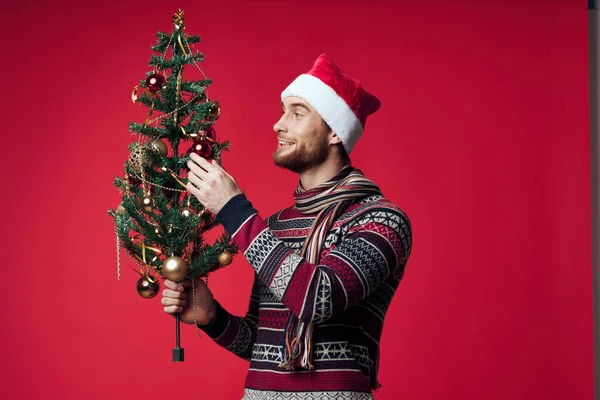 Noel Baba şapkalı bir adam Noel ağacı süslemesi kırmızı arka plan — Stok fotoğraf