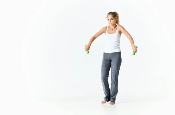 Mujer deportiva con mancuernas en las manos entrenamiento gimnasio luz fondo —  Fotos de Stock
