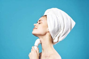 Kafasında havlu olan kadın yüz temizleme, mavi arka plan.