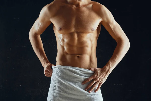 Sportig man med en pumpad muskulös kropp i en handduk mörk bakgrund Stockbild