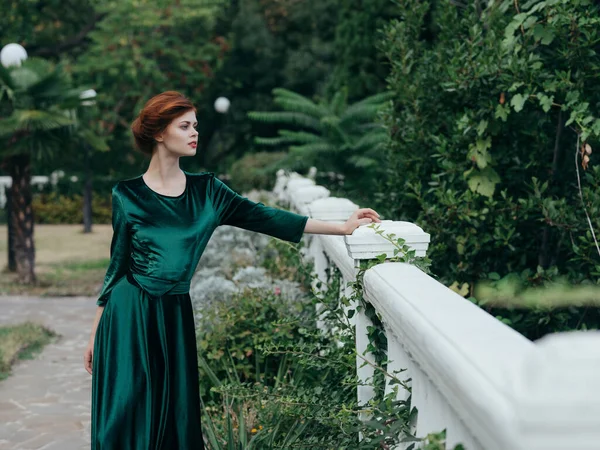 Γυναίκα σε πράσινο φόρεμα με τα πόδια στο πάρκο πολυτέλεια ποζάρουν — Φωτογραφία Αρχείου