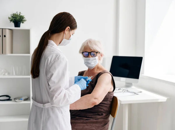 Sjuksköterska som ger en injektion till en äldre kvinnas läkemedel immunitetsskydd — Stockfoto