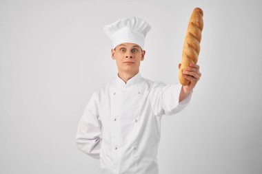 Neşeli erkek aşçı bir ekmek fırınını ısırıyor.