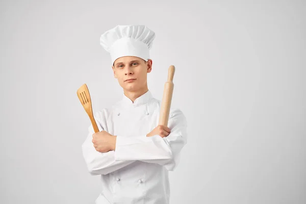 Chef di sesso maschile con un tappo sulla testa e stoviglie sfondo leggero — Foto Stock