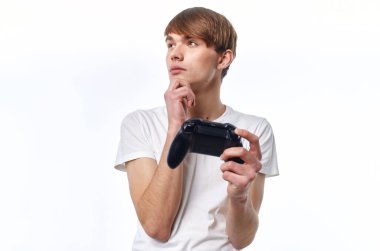 Elinde joystick olan beyaz tişörtlü bir adam hobi hayatı yaşıyor.