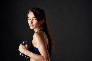 Elinde dambıllar, elinde spor salonu olan ince bir kadın.