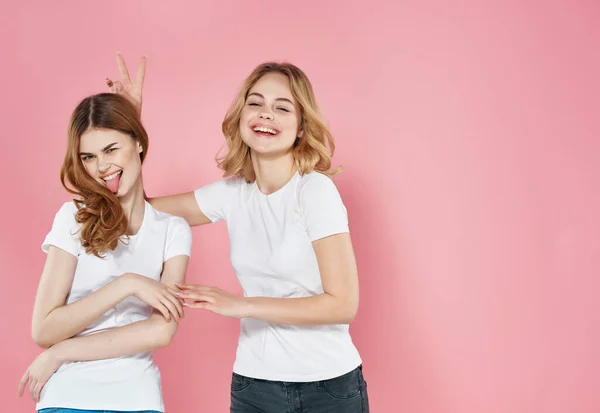 İki beyaz tişörtlü kadın modern yaz tarzı arkadaşlık duyguları pembe arka plan — Stok fotoğraf