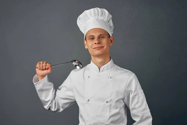 a chef with a cap on his head a scoop in his hands cooking food dark background