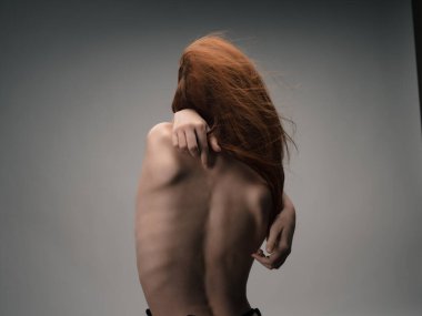 Kızıl saçlı kadın arkadan el ele tutuşuyor.