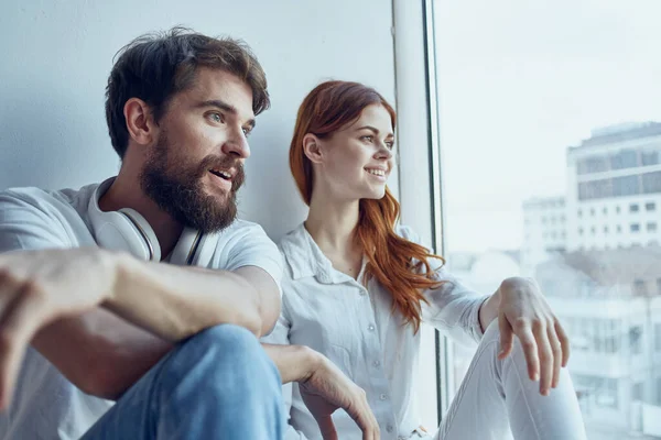 Férfi és nő ül az ablak mellett fejhallgatóval együtt apartmanok — Stock Fotó