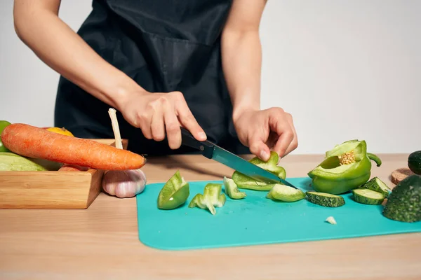 Donna in grembiule nero affettare verdure cucina cucina cibo — Foto Stock
