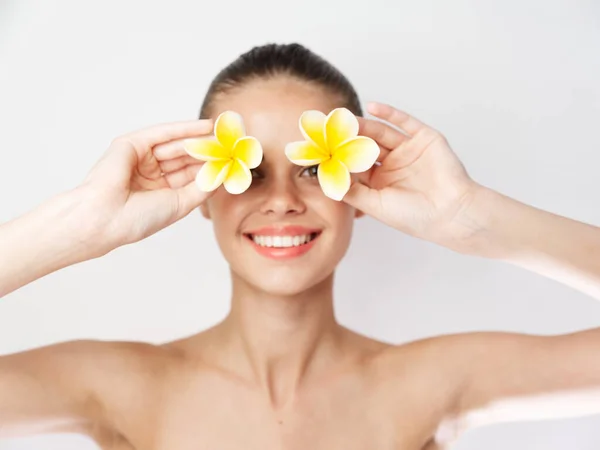 Mujer alegre con flores amarillas cerca de la cara hombros desnudos sonrisa fondo aislado — Foto de Stock