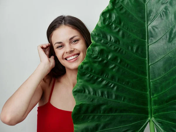 Kırmızı mayo giymiş gülümseyen kadın yeşil palmiye yaprağı cazibesi — Stok fotoğraf