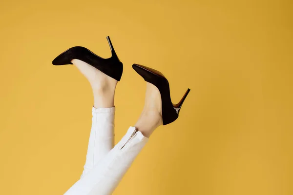 Samice převrácené nohy v černé obuvi oříznuté pohled žluté pozadí — Stock fotografie