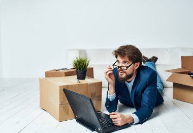 Ucuz bir adam dizüstü bilgisayarın önünde yerde yatıyor. 