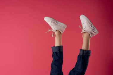 Beyaz spor ayakkabılarıyla baş aşağı duran kadın bacakları pembe arka plan modası