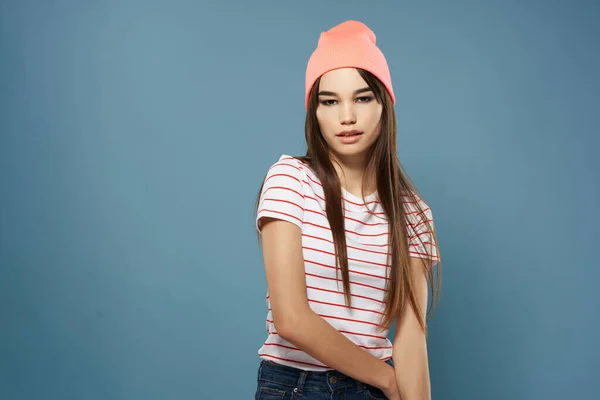 Όμορφη μελαχρινή κρατώντας τα μαλλιά ροζ καπέλο μοντέρνο στυλ μπλε φόντο — Φωτογραφία Αρχείου