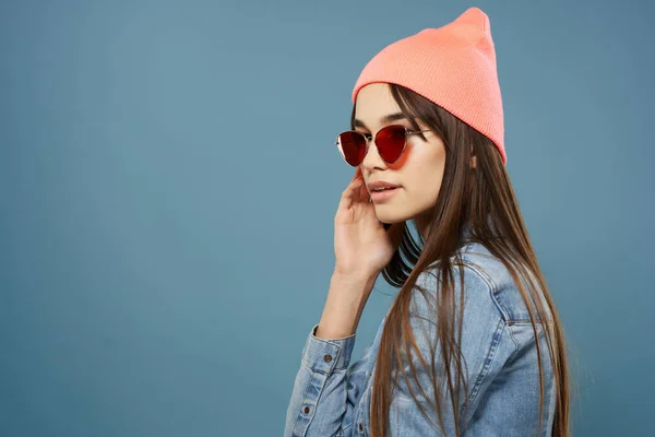 Vrouw in roze hoed zonnebril denim jas hipster blauwe achtergrond — Stockfoto
