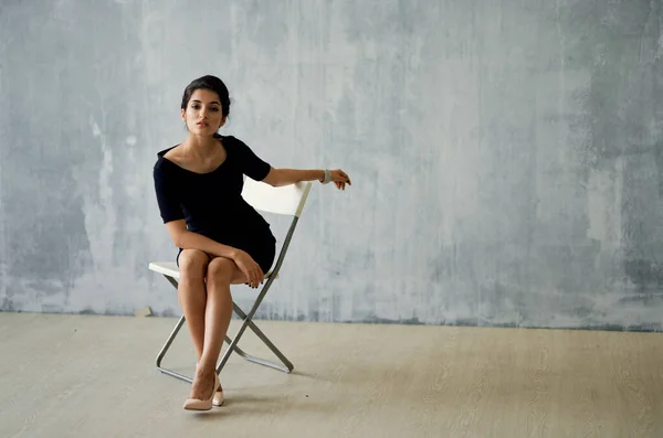 woman sitting on a chair in a black dress posing