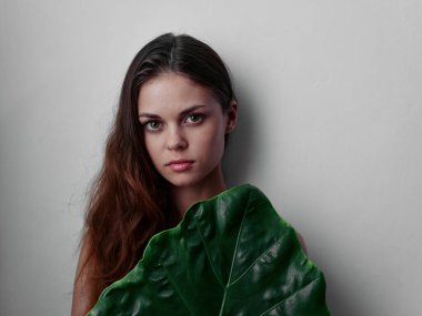 Yeşil stüdyo yaprağının arkasına saklanan çıplak omuzlu kızıl saçlı kadın.