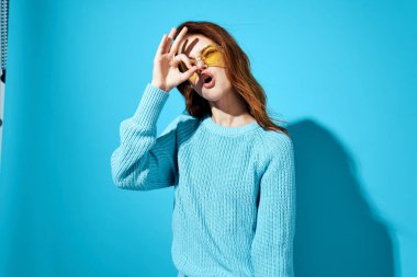 Mavi süveterli, mavi arka planlı kadın.