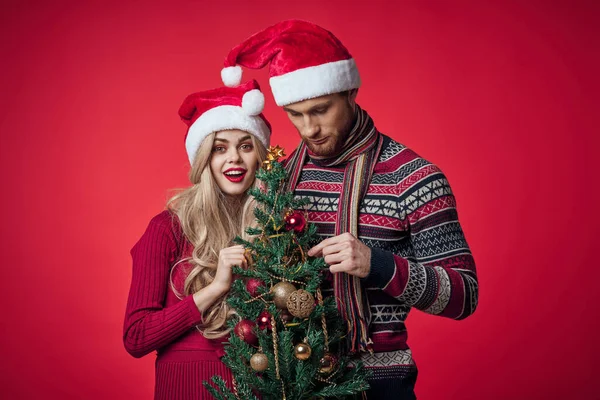 Mann und Frau in Neujahrskleidung zusammen Weihnachtsgeschenke roter Hintergrund — Stockfoto