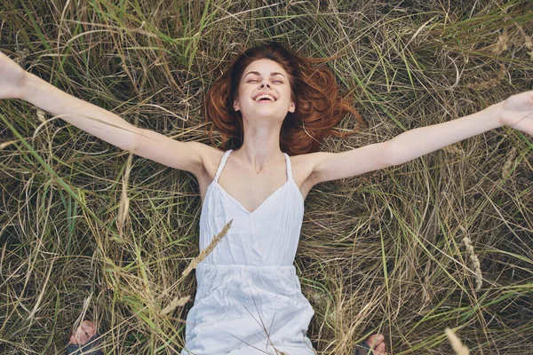 Güzel, neşeli bir kadın yaz tatilinde çimlerde yatıyor. — Stok fotoğraf